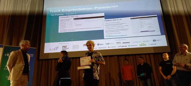 En la premiación, Eli hablando y Nico sosteniendo los premios